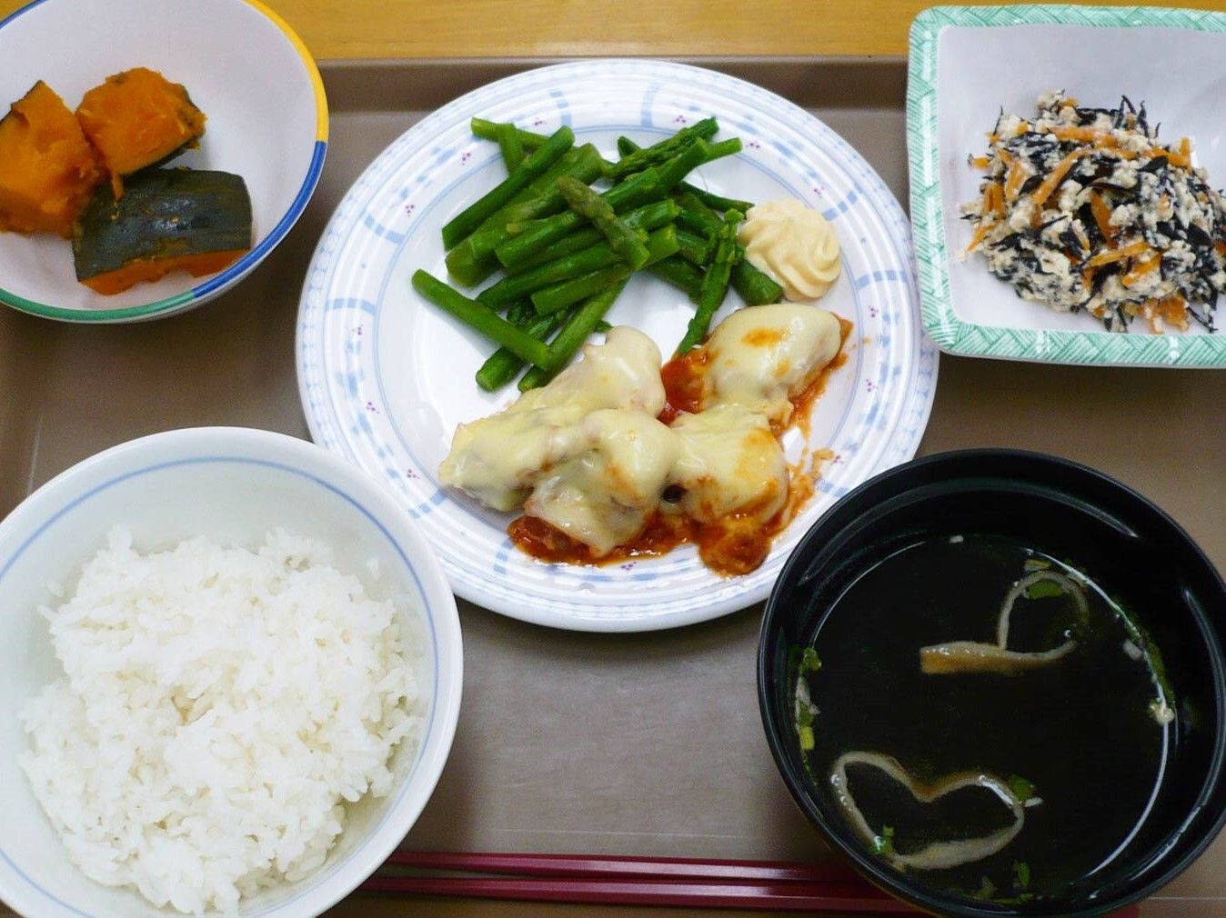 肉の和え物のようなものがメインとして真ん中に置かれ、囲むようにしろご飯や吸い物、かぼちゃの煮物、白和えなどが置かれている。