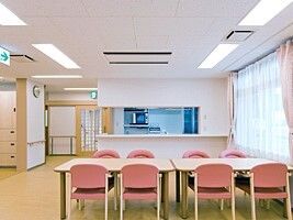 対面式キッチンがある共有スペースにはピンクの椅子がセットされたダイニングテーブルが置かれている。