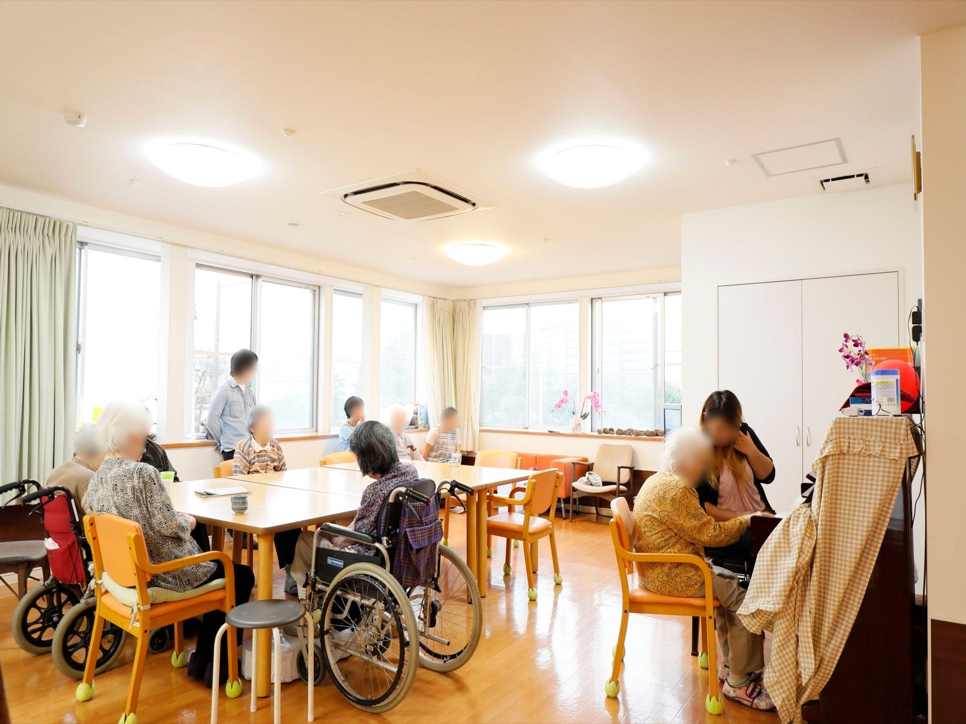 開放的なリビングで、椅子の脚にはテニスボールがはめ込まれている。壁際にピアノが置かれており、スタッフと一緒に練習をしている。