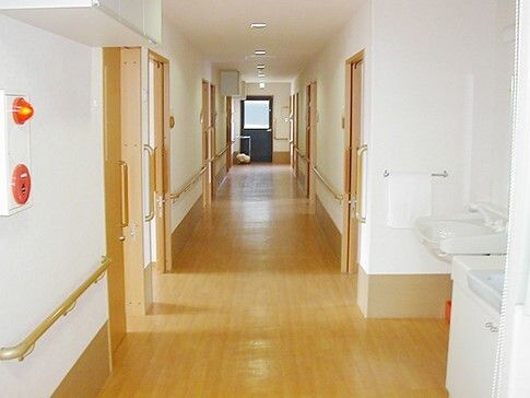 右側には洗面所があり、車いす対応の造り。正面にあるまっすぐな廊下の両サイドに手すりがあり、居室のドアもある。