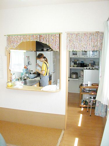 黄色いTシャツにエプロンを付けた女性スタッフがキッチン内で調理をしている様子。