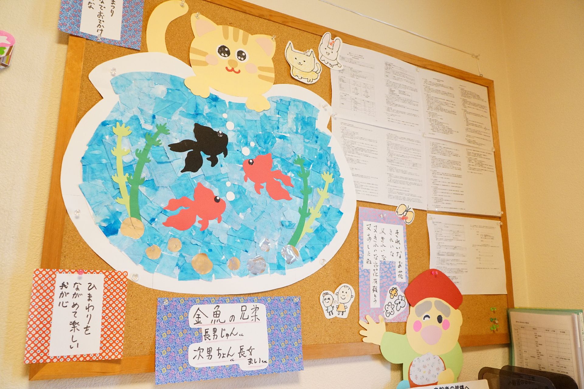 掲示板に飾られている、入居者・スタッフが作成した猫と金魚鉢の絵