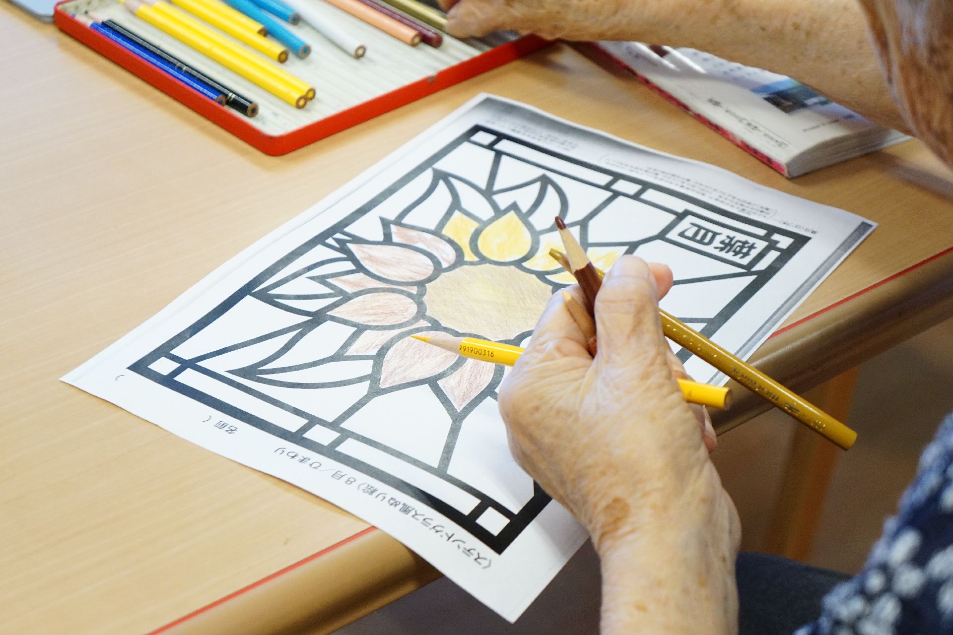 色鉛筆で花に色を付ける塗り絵に取り組むレクリエーション