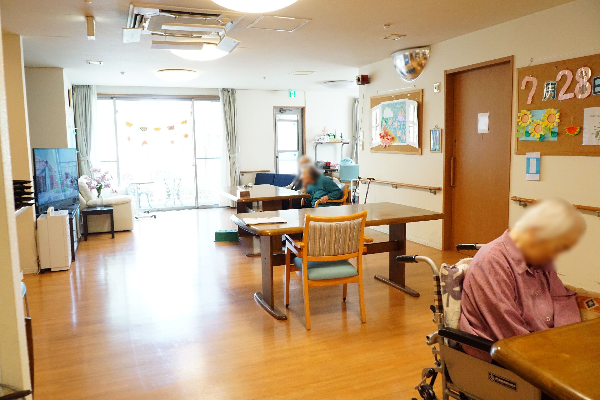 大きな窓が設置され、入居者が自由に時間を過ごしているリビング