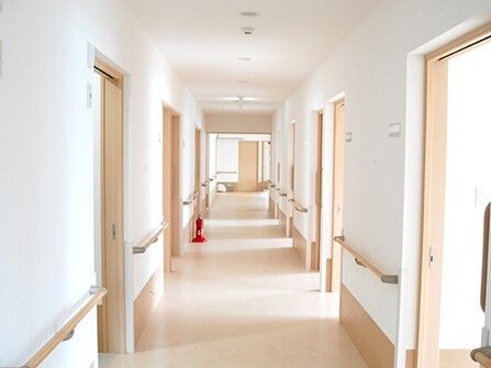 まっすぐな廊下の両サイドに居室のドアと手すりがあり、廊下には消火器も設置されている。