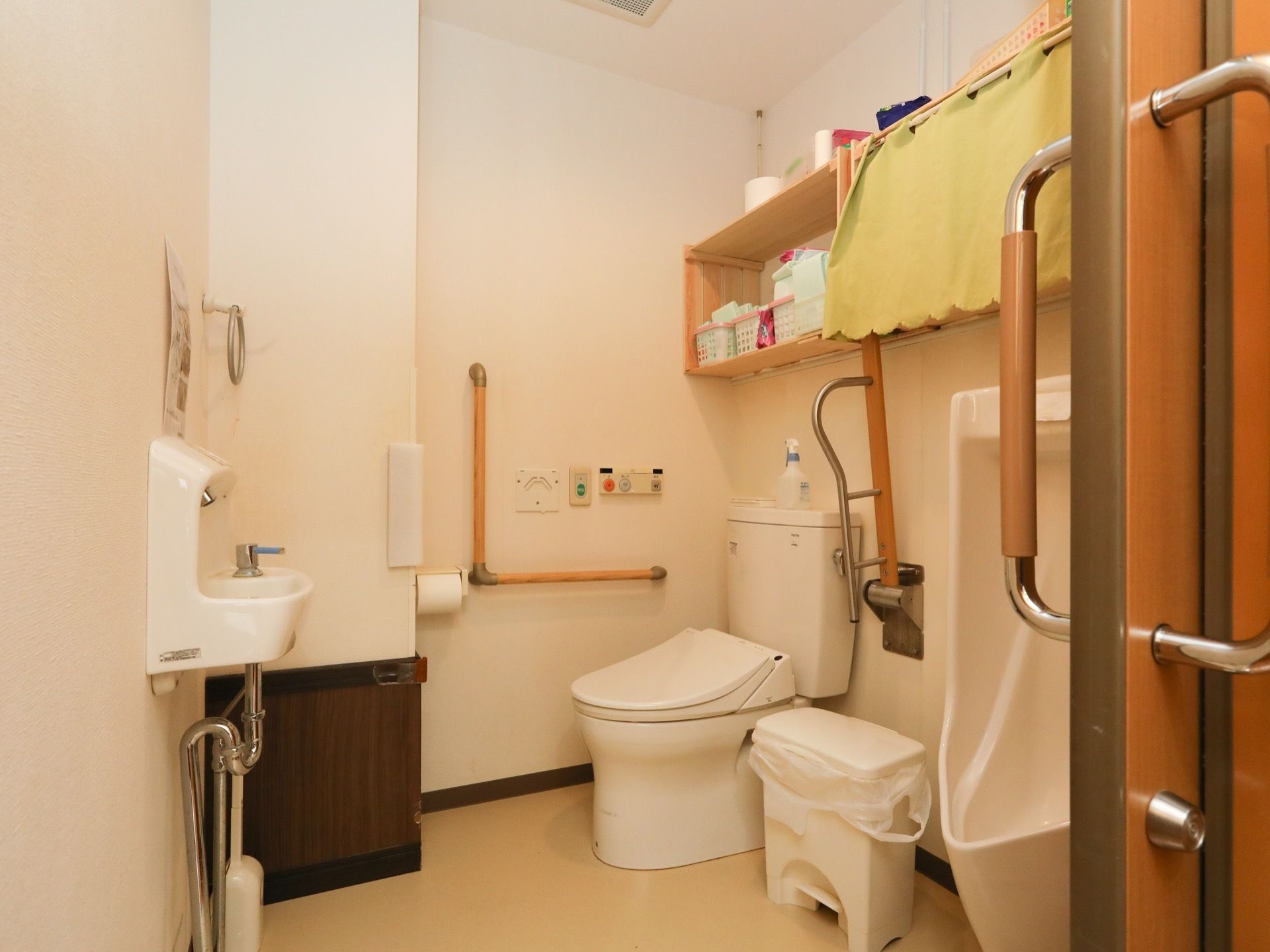 大きな取っ手がついた引き戸を開けると共用トイレがある。手前に男性用便器、奥に男女共用の便器が設置されている。