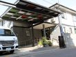 大きな屋根が付いた玄関には階段だけでなくスロープもあり、ホームの車が止まっている。