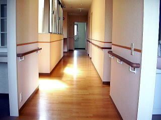 フローリング仕様の床の廊下の様子。壁に満遍なく手すりが取り付けられている