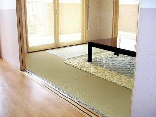 たたみの部屋に小さな家庭用のテーブルが置かれている様子。２面に窓があり外につながっている