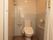 温水暖房便座付きのトイレである。入口から移動用の手すりと、座位保持用の可動式の手すりが設置されている。