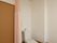 居室のドアの横にトイレが設置されている。ピンクのカーテンでスペースを仕切られるようになっており、天井に換気扇がある。