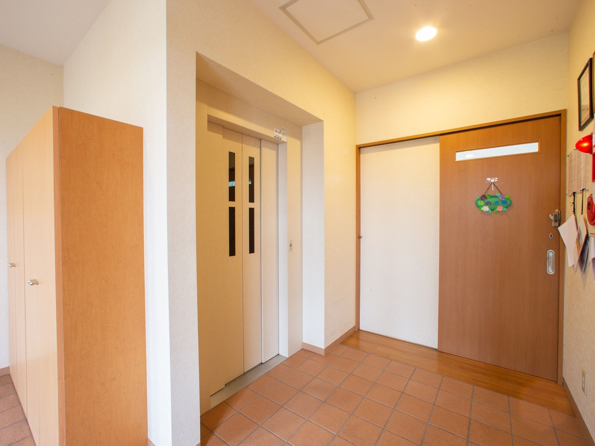 施設内に完備されている白い扉のエレベーター。そばには収納棚が設けられ、壁には緊急非常通報装置が設置されている。