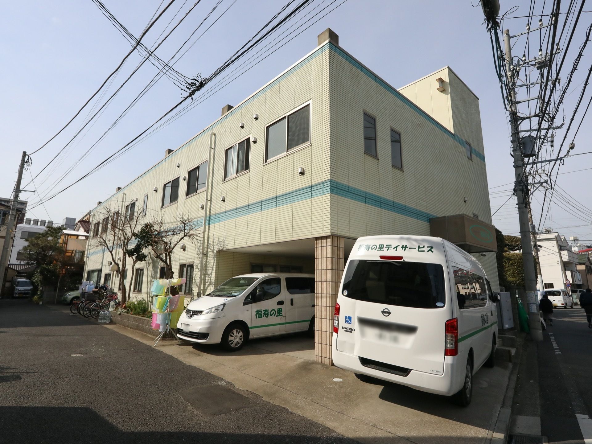 白を基調とした２階建ての建物である。福祉車両が２台停められている。駐輪場が設けられており、自転車が複数台置かれている。