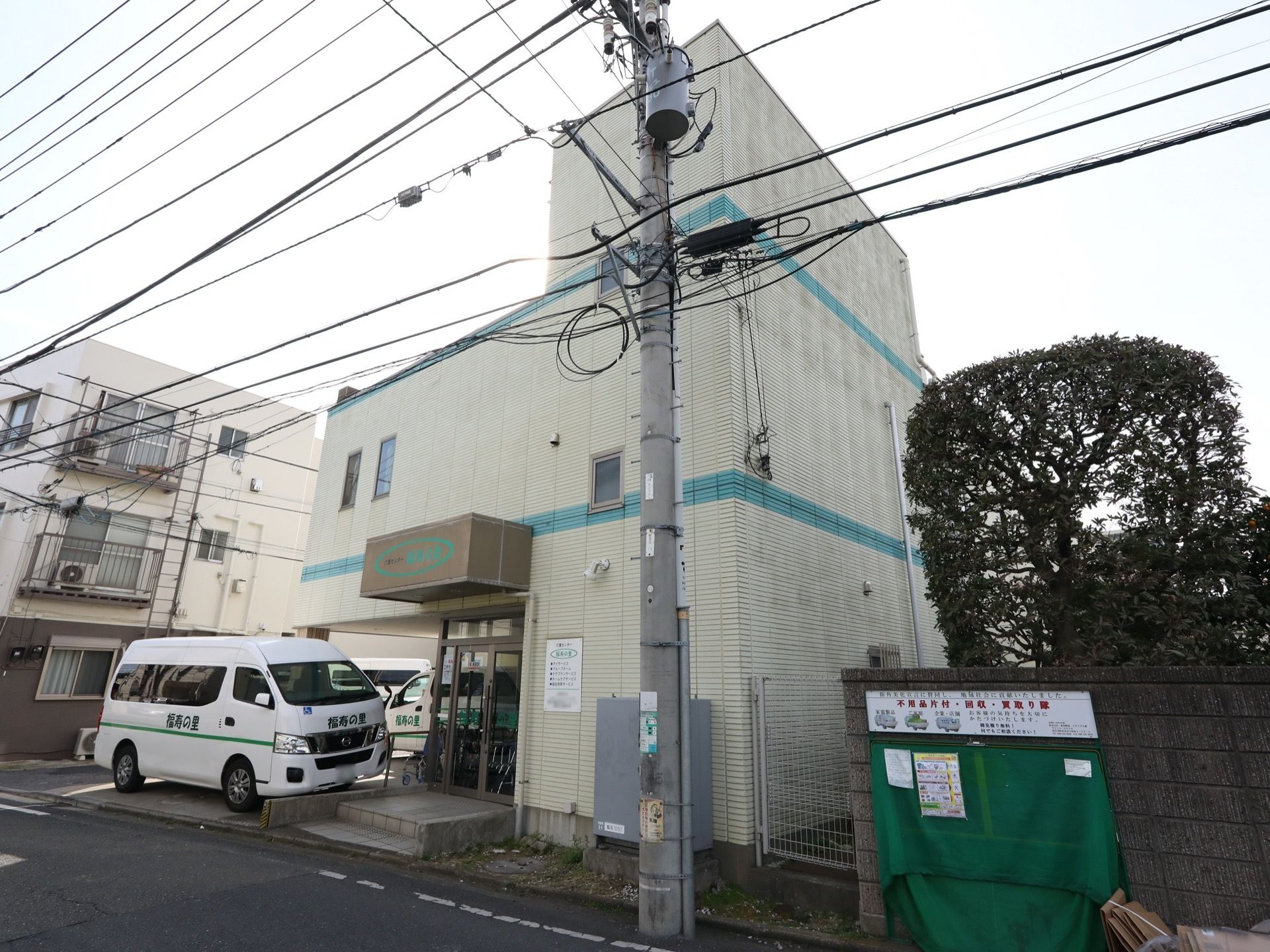 壁にブルーのラインが入った３階建てのホームである。道路側から階段を登る入口もある。サイドにホーム名が記された車が停められる。