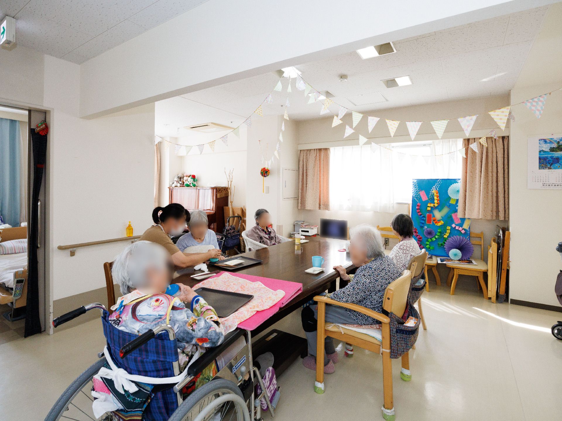 広間の長机に集まり団欒している入居者様
