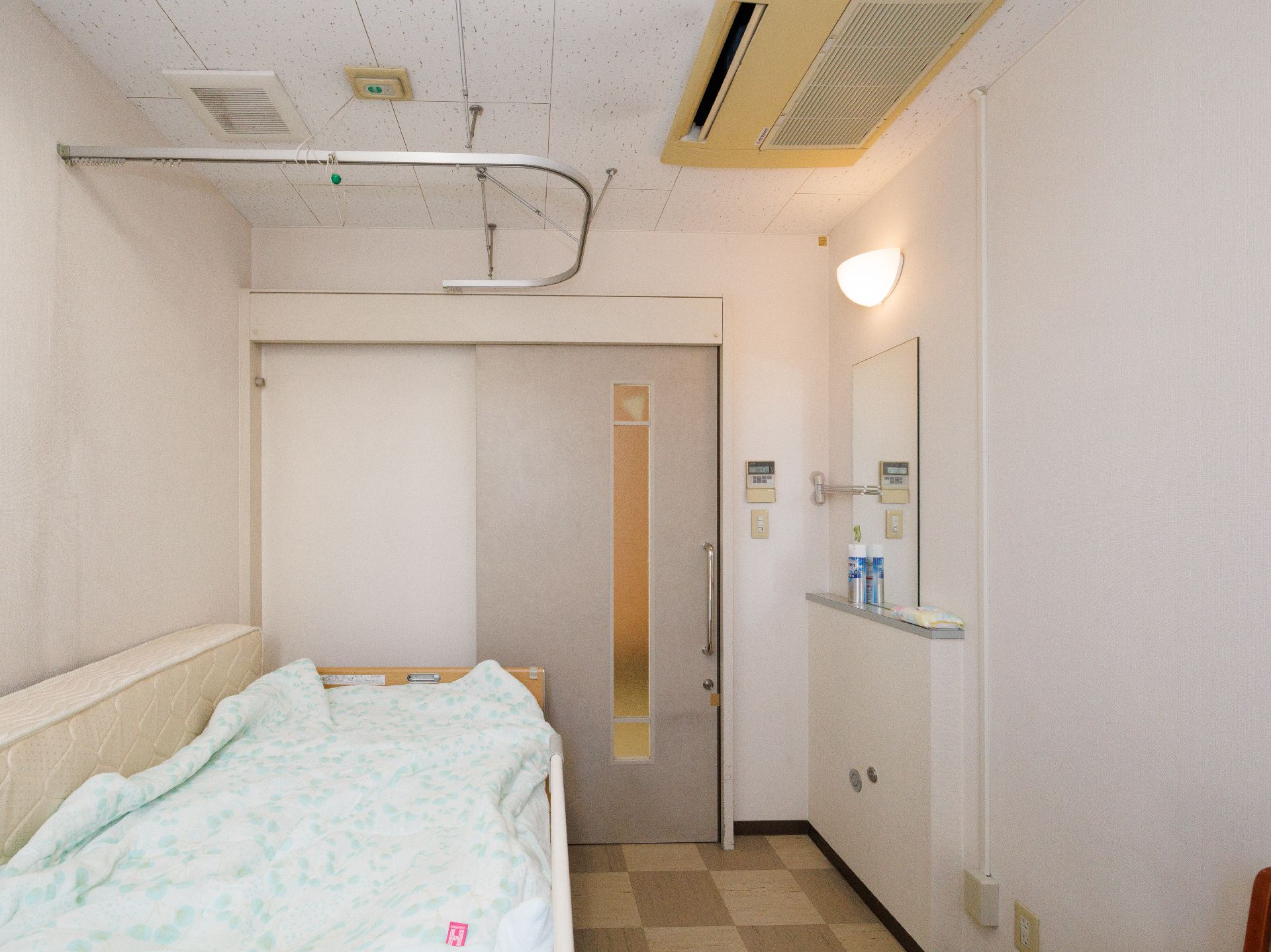 鏡とベッドのある白い部屋