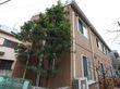 施設はブラウンの外壁で２階建てである。建物のそばには背の高い木が植えられていて、その周りにフェンスが設置されている。