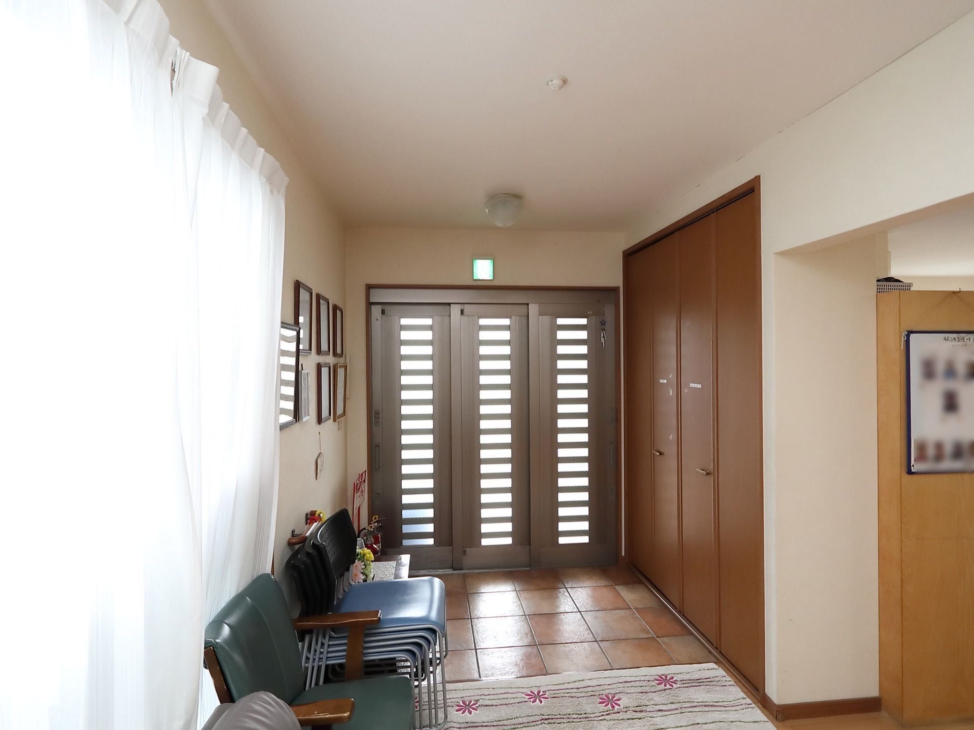 入口扉は引き戸になっている。入口前には折れ戸式の下駄箱が備えつけられている。床には玄関マットが敷かれている。