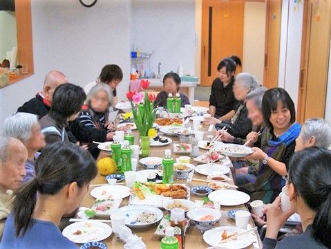 大きめのテーブルにスタッフと高齢者が座って食事を摂っている様子