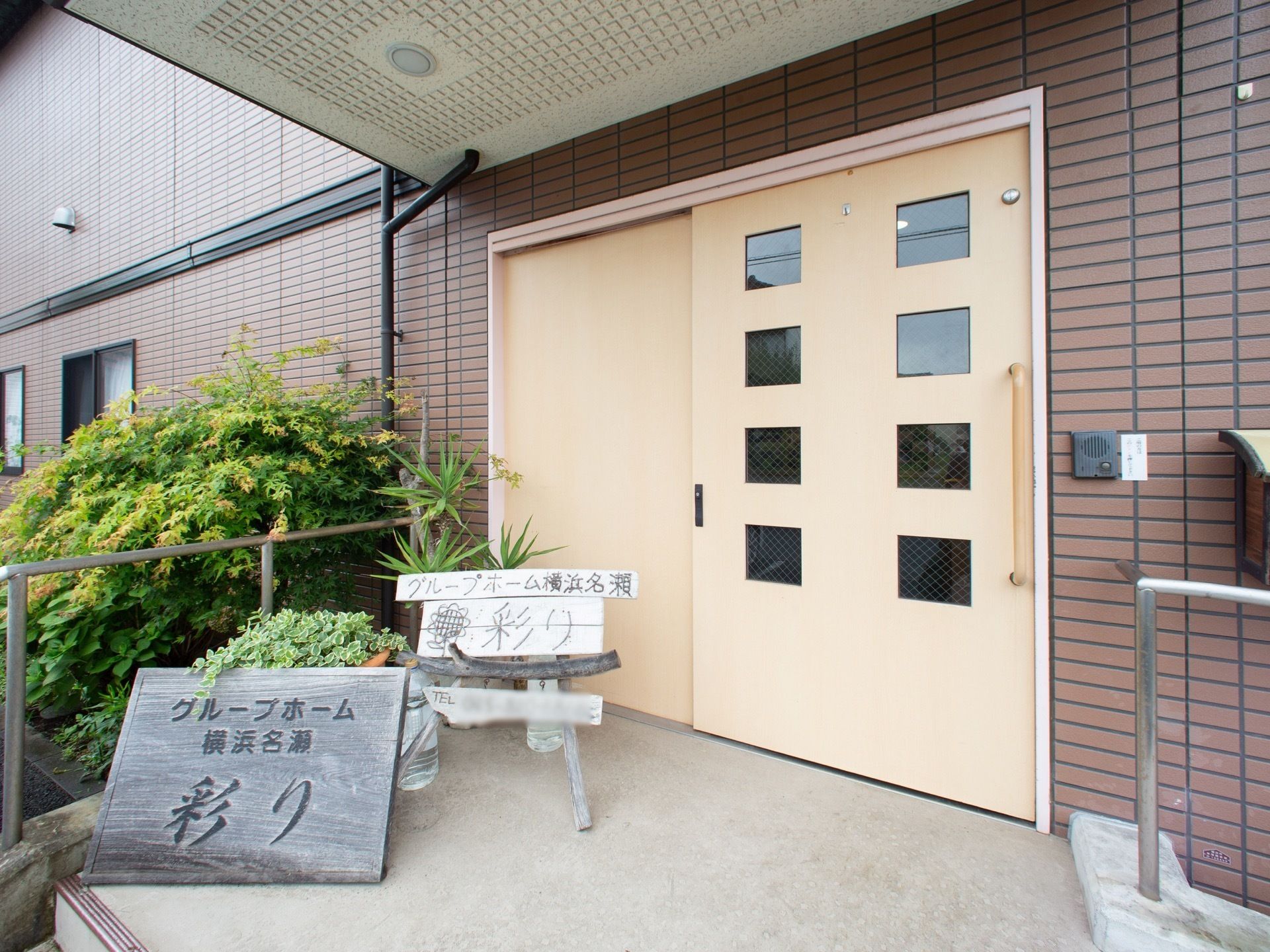 スライドタイプの玄関ドアと手作りの看板が置かれた玄関
