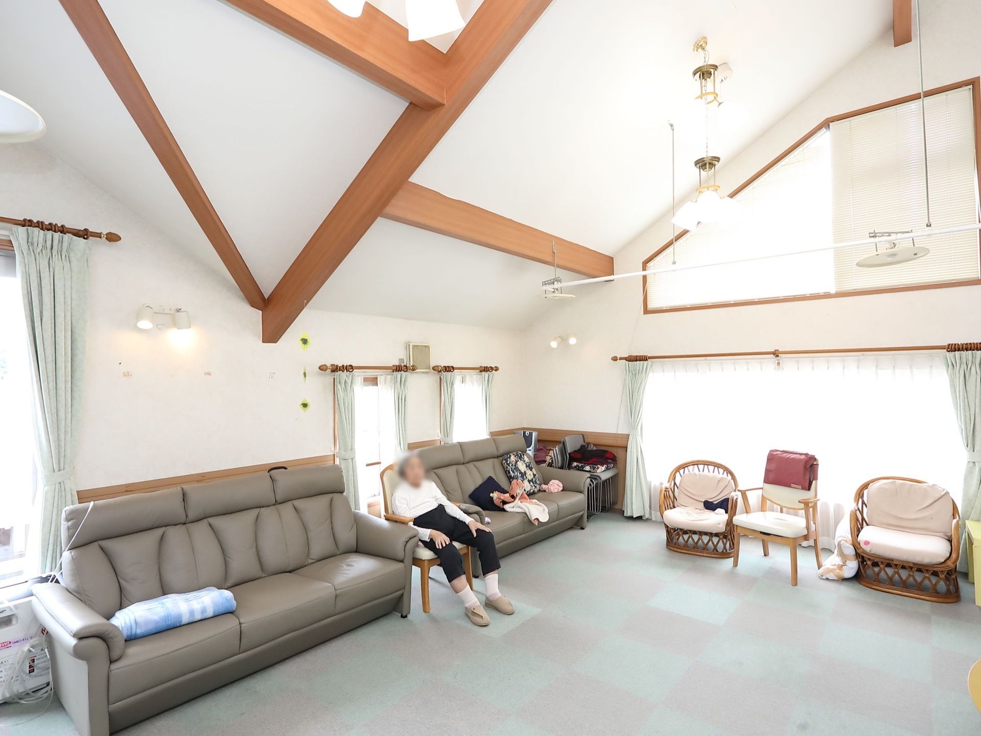 広々とした屋根裏の空間に、籐椅子やソファなどが置かれている。天井や壁が白く、窓が多いので、明るく開放感がある。