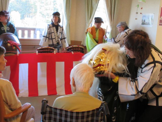 お祭りを楽しでいる高齢者と出演者。施設内で行われているイベントの一環