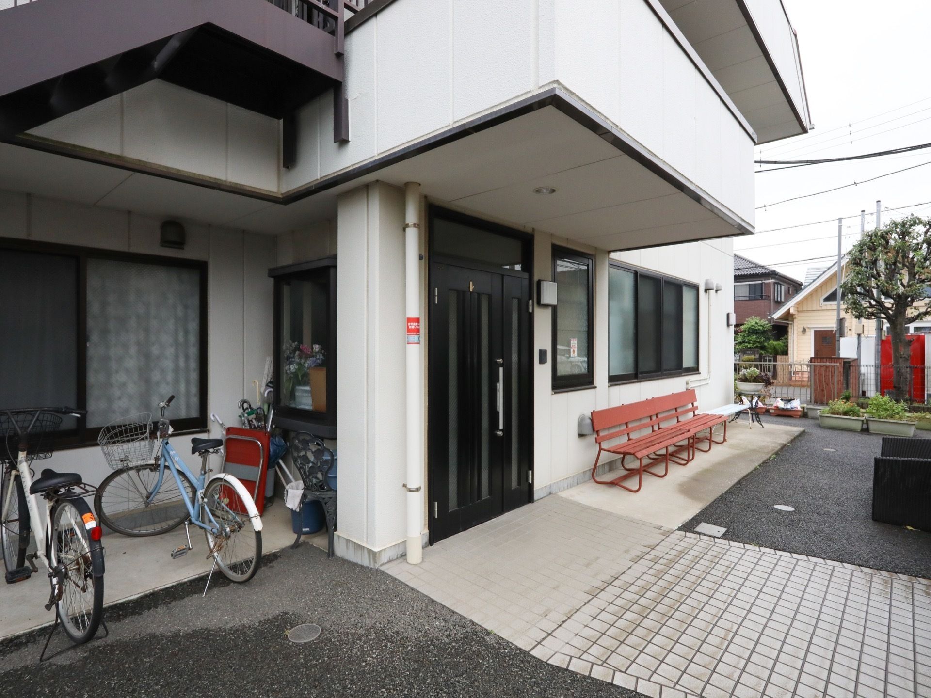 民家の雰囲気がただよう、エントランスである。屋根に照明を完備。壁側には、複数人が腰かけられるベンチがある。
