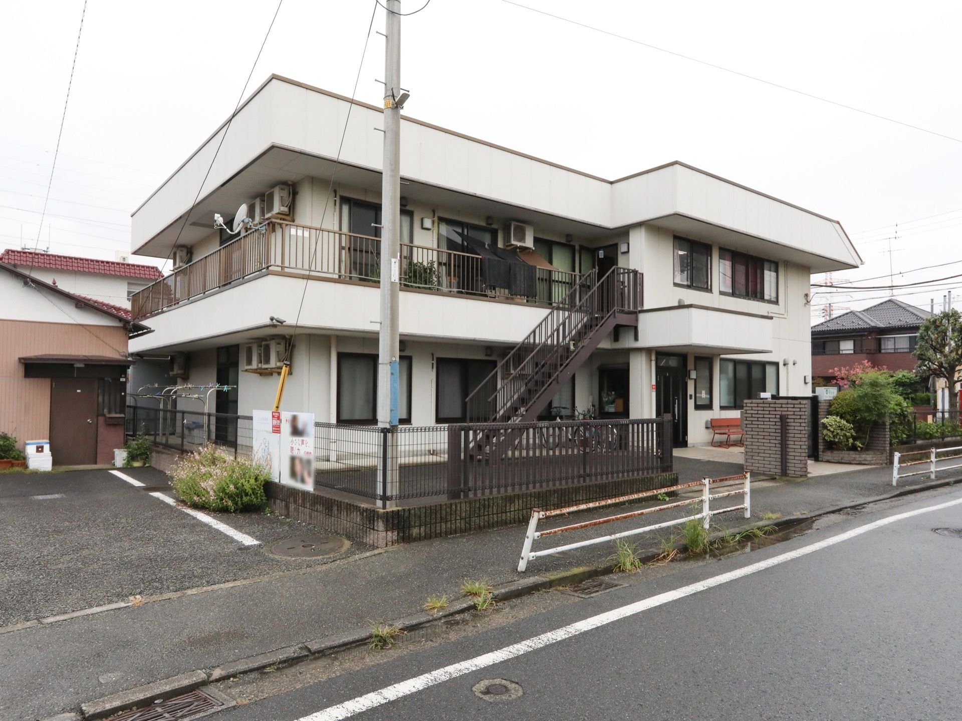 白色で統一された、２階建ての施設である。非常口階段も備えられている。そばに駐車場が完備されている。