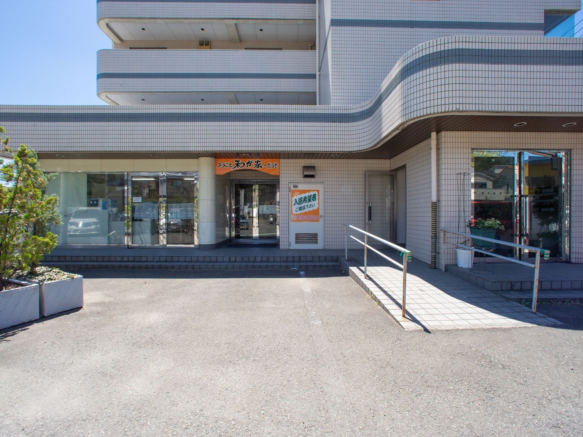 施設の入り口は少し奥まった場所に設置し、出入りが見えにくいように配慮している。手すり付きのスロープを設けて、安全に出入りすることができる。