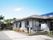 平屋建ての建物にはグレーの屋根が付き、周辺には洗濯物干しざおや季節の花がある。