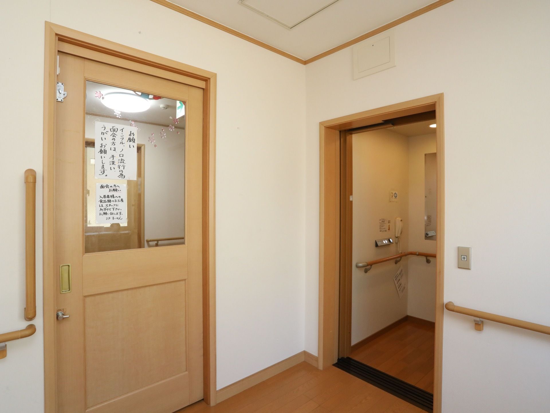面会の方へのお願いが貼られた扉の横にエレベーターが設置されている。エレベーター内には手すりや鏡が備わっている。