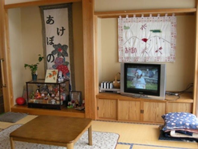 テレビがあり、掛け軸や日本人形が飾られている老人ホームの和室