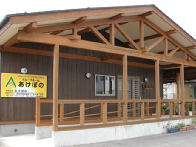 こげ茶色の壁に黄色い看板が特徴の老人ホーム施設外観