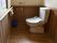 壁面や手すりにも木材を利用し、温かみある空間のトイレである。温水洗浄便座器や緊急呼び出しブザーが設置されている。