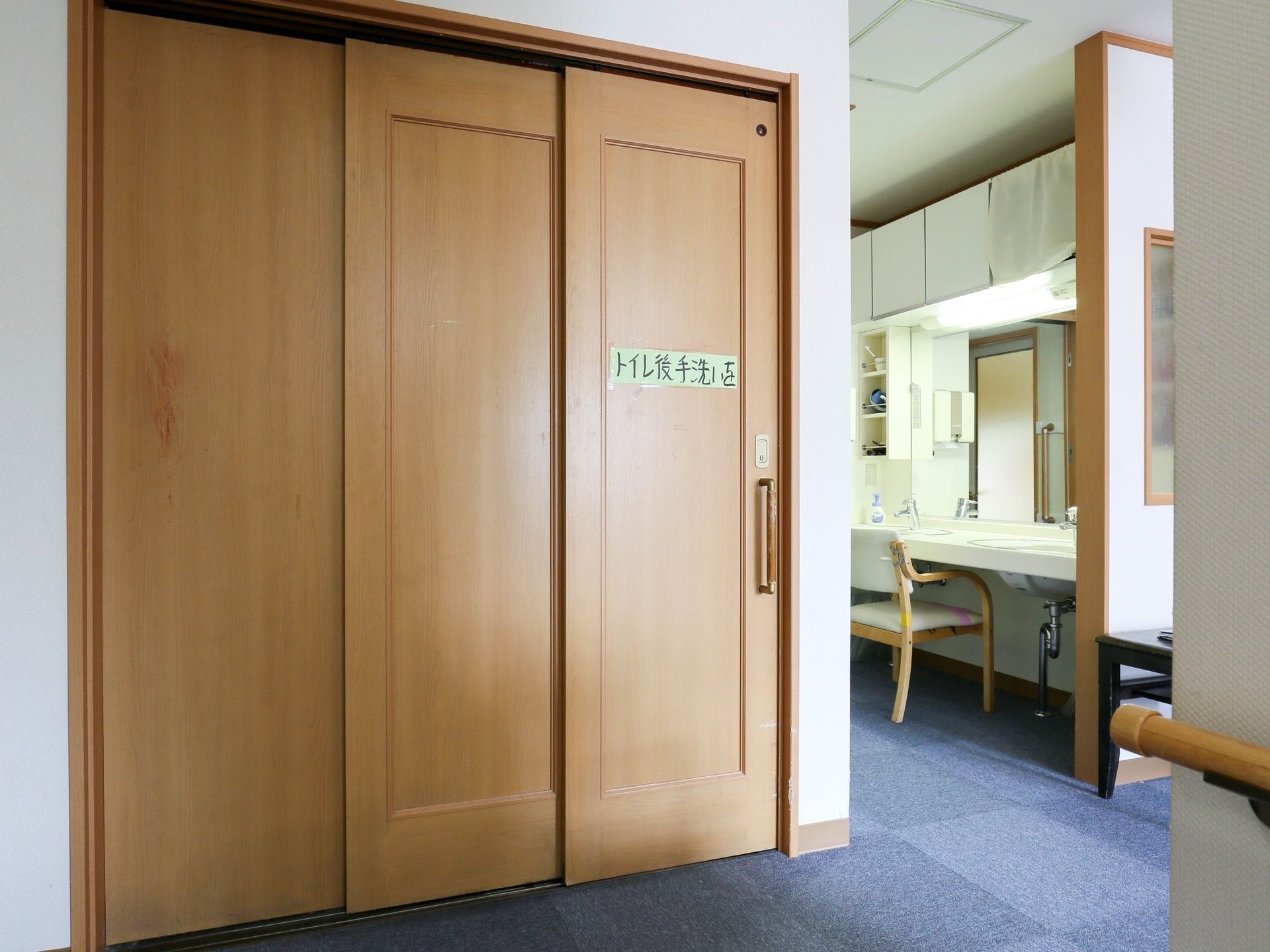 トイレのドアは木製のスライドタイプである。縦長の取っ手が付いている。ドアには手洗いを促すメモが貼ってある。