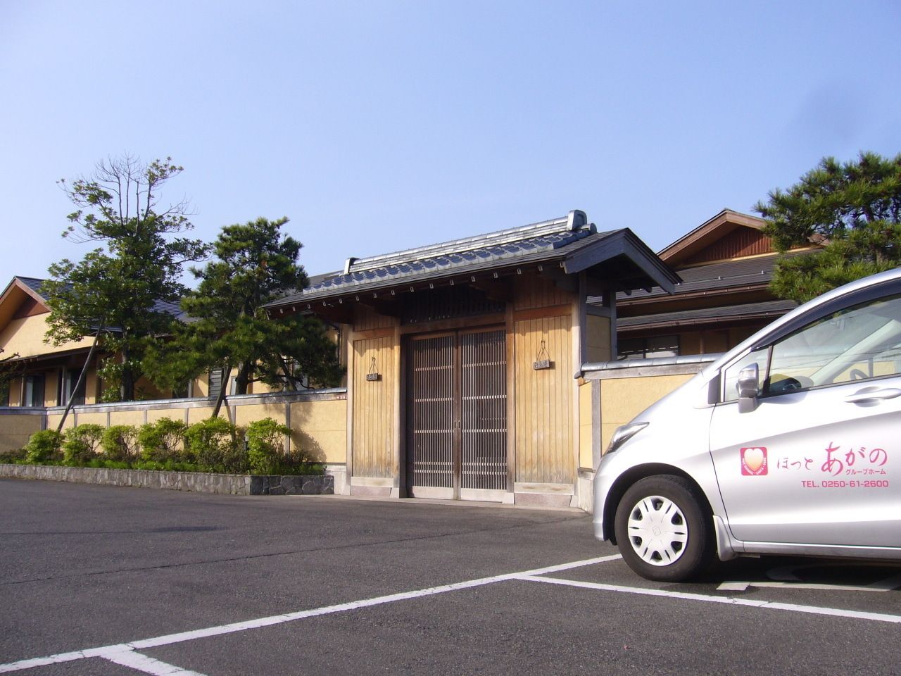 手前に駐車場スペースがある施設の敷地の様子。日本家屋風デザインの入り口