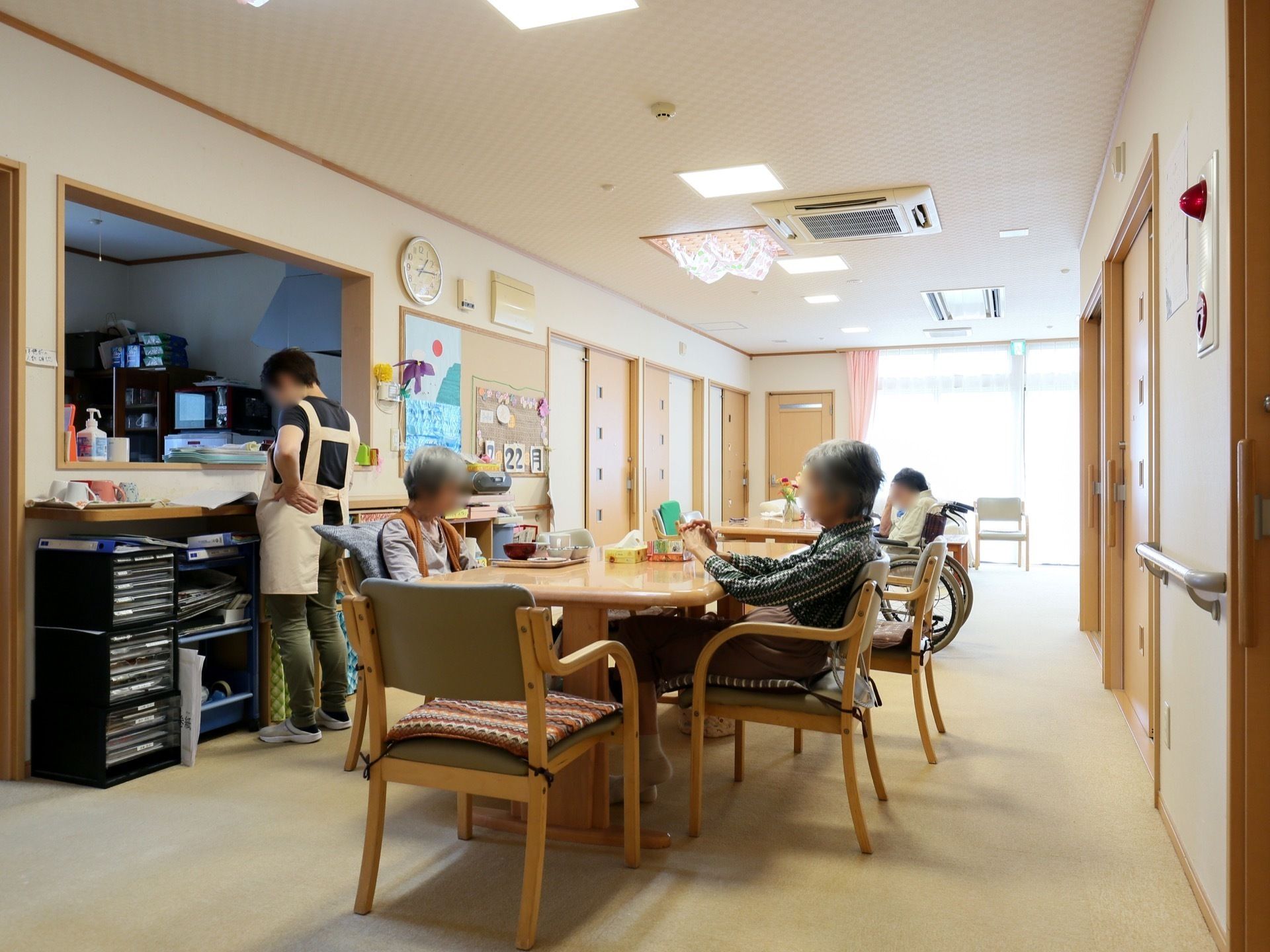 家庭のリビングのような木の風合いが漂う場所。長机が一つとイスが数脚置いてある様子