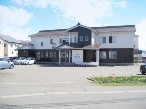 笑顔でこちらを向いている施設のスタッフと車いすに乗っている高齢者の様子。施設で写された写真