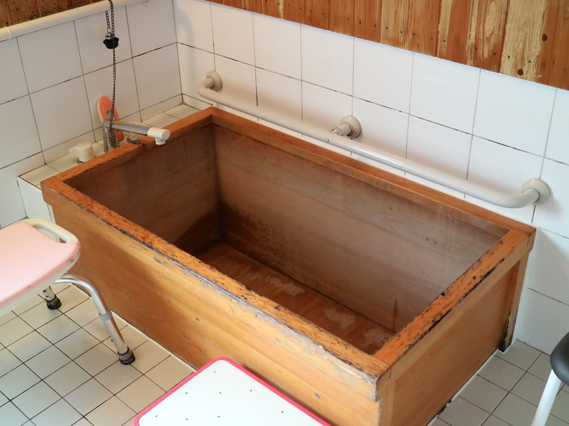 浴室の浴槽は、ヒノキ材が使用されている。浴槽の横の壁には手すりが設置されており、シャワーチェアが置かれている。