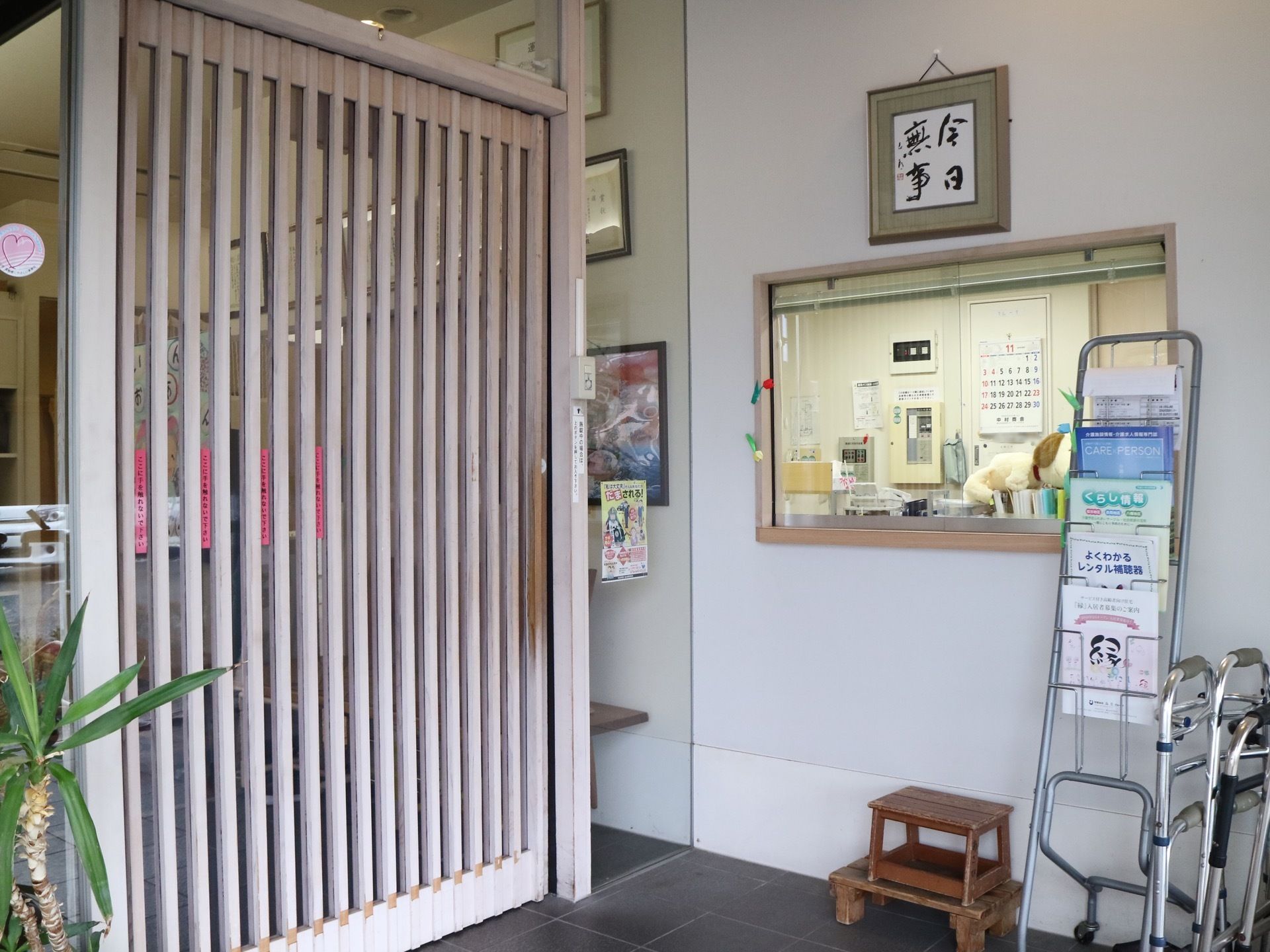 右側に受付がある。受付の窓はガラス張りになっており、室内を見渡すことができる。床には、木の踏み台が置かれている。