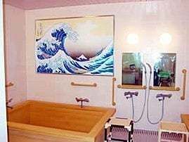 絵画のようなものが掲げられている浴室。シャワーチェアや手すりがある高齢者用の浴室