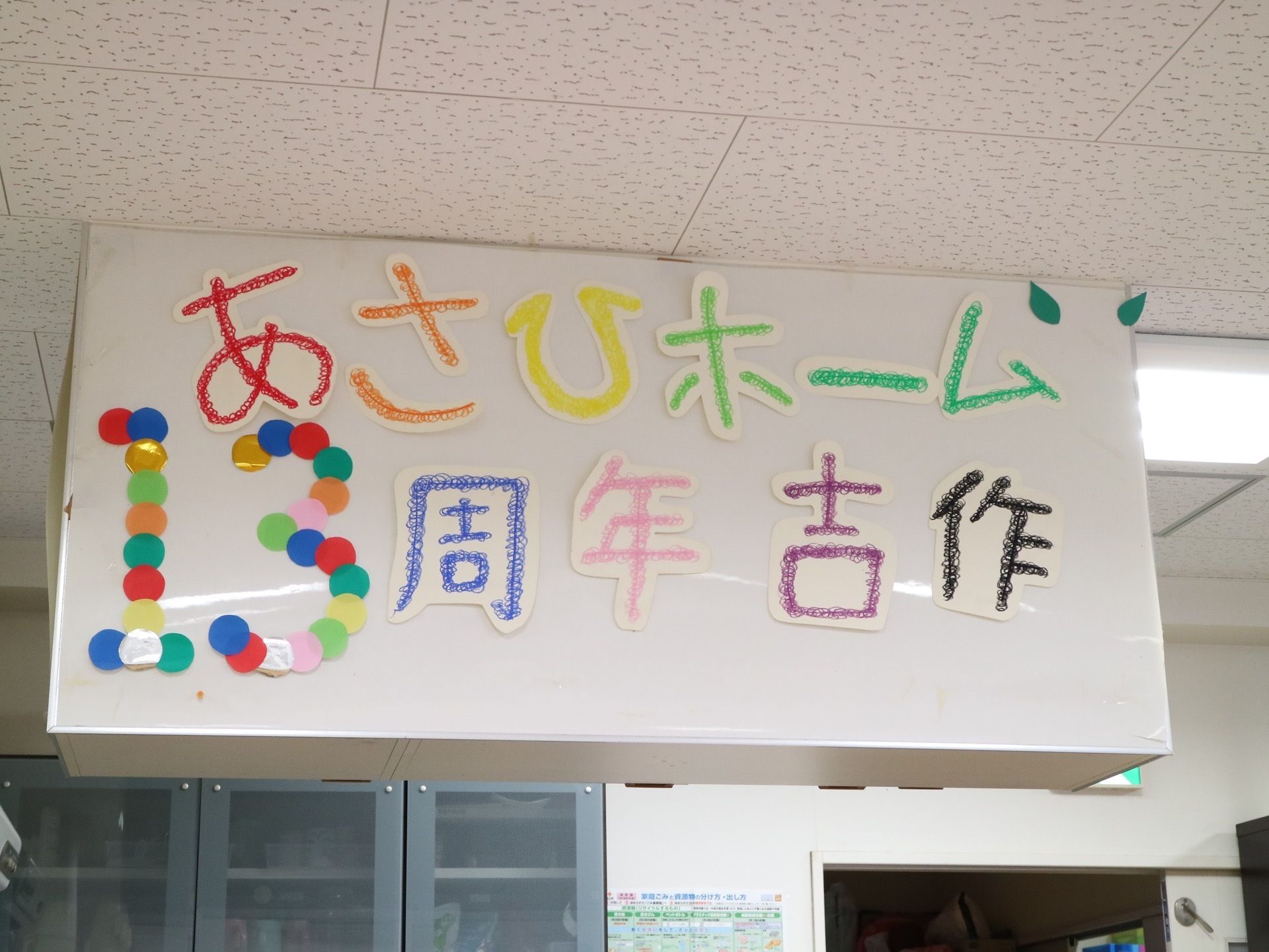 さまざまなカラーを使い、施設名や周年が書かれた作品である。天井に設置され、大きなサイズで存在感がある。
