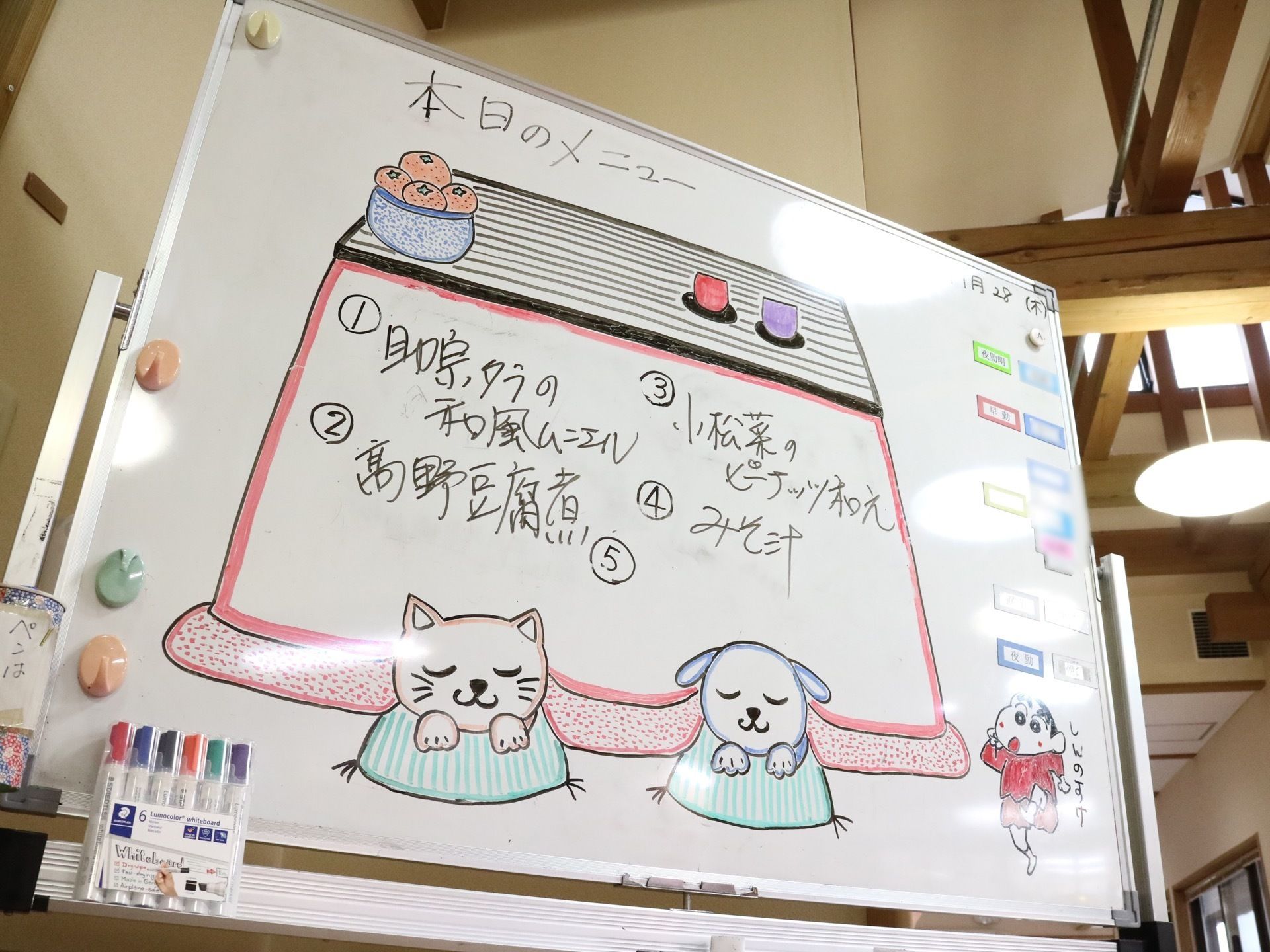ホワイトボードに記入された当日の食事内容である。きれいなイラストとともに、メインの献立や副菜が記載されている。