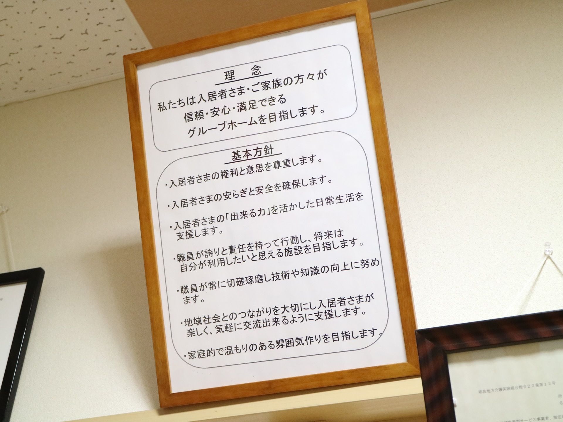 茶色い木製の額縁が、施設内の天井近くに紐で吊られて飾られている。基本方針と理念が白い紙に黒い字で書かれている。
