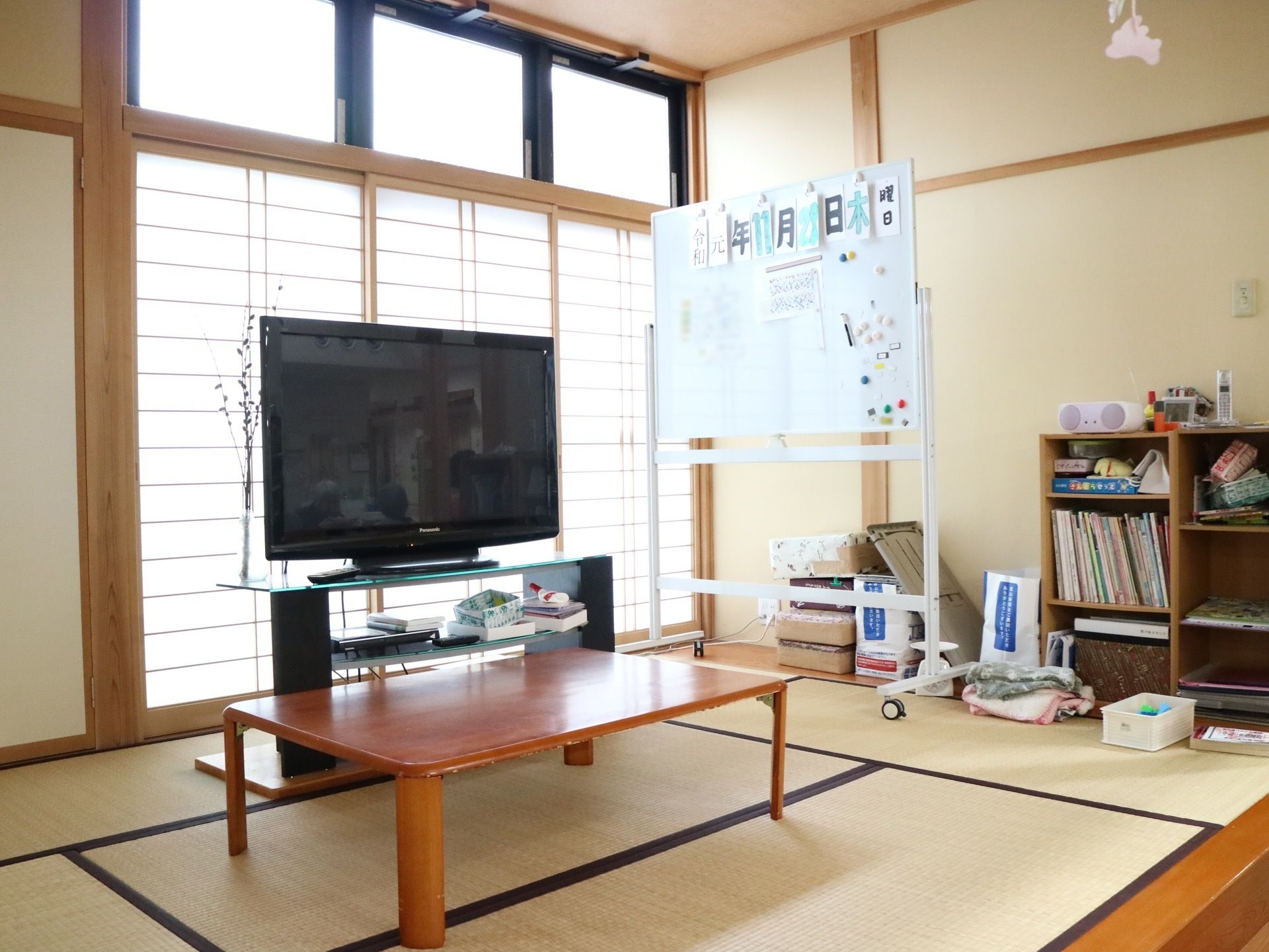 畳が敷かれた共有スペースである。中央に座卓があり、その奥に大型液晶テレビが置かれている。窓は障子が嵌められている。