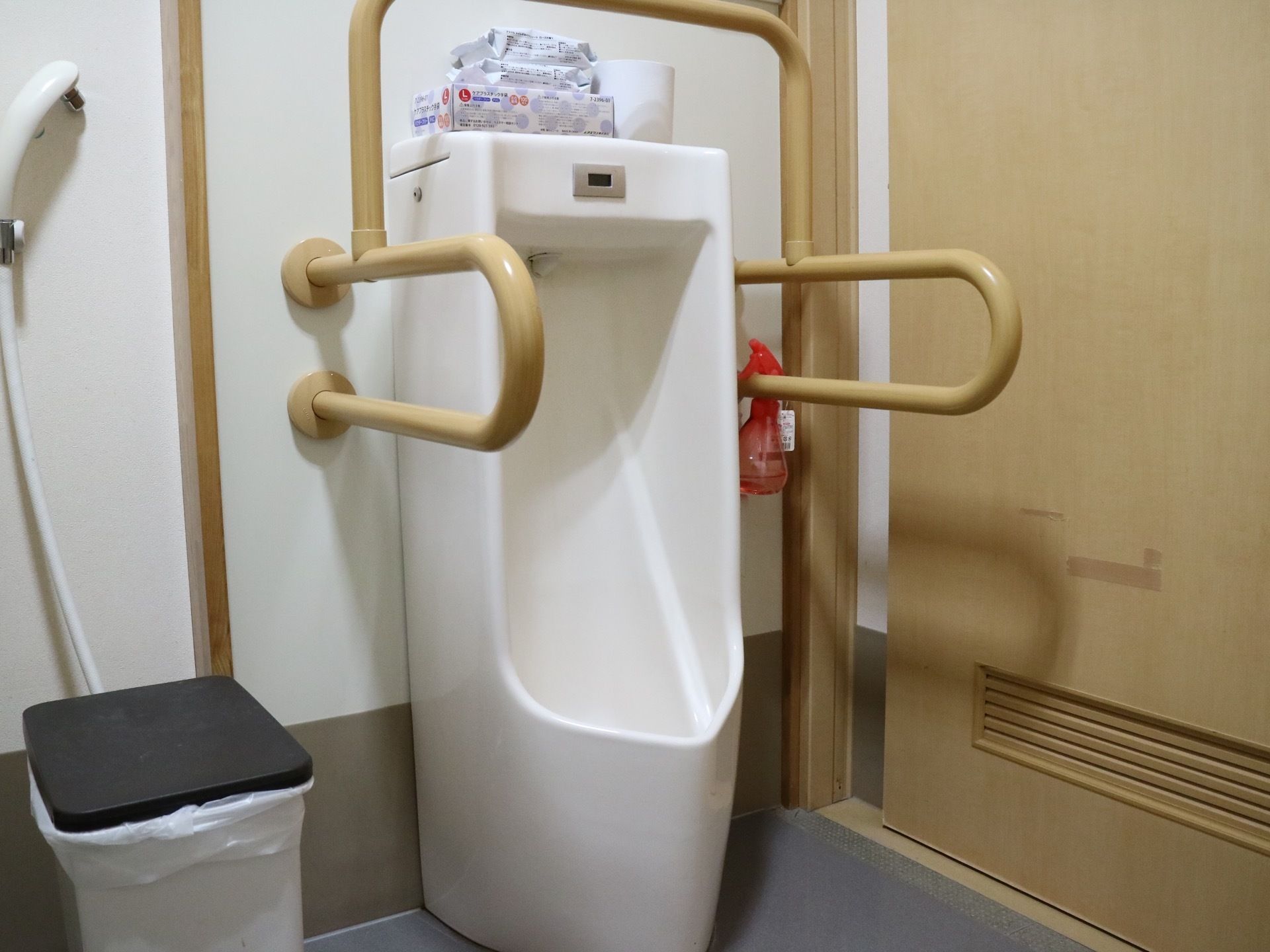 男性用の立位式トイレが用意されている。中央に白い便器があり、その両側に茶色のＵ字型の手すりが設置されている。