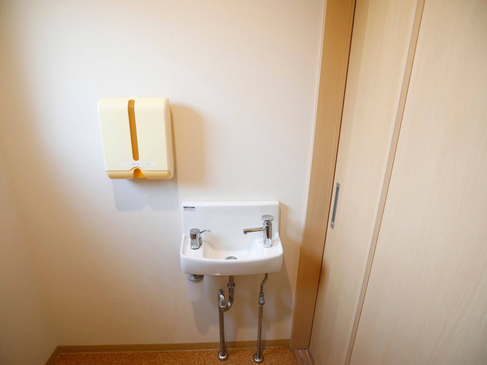 日差しが入る、明るいトイレ空間。清潔感ある、白色の手洗い場が完備されている。ソープディスペンサーも備えられている。