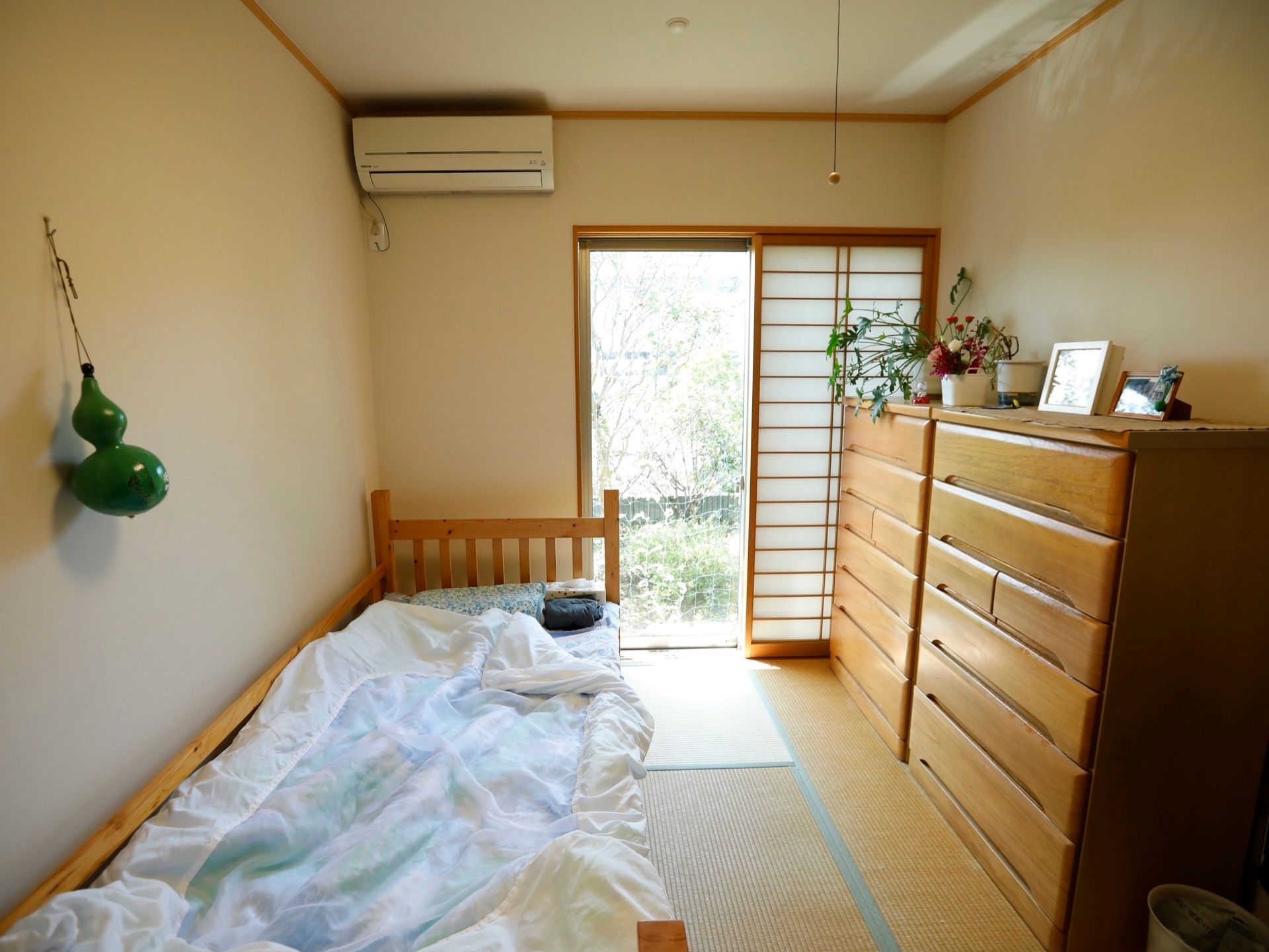 落ち着いた雰囲気の和部屋である。衣類などを収納する、家具が２台置かれている。棚上には生け花などが飾られている。