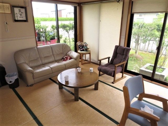 畳の部屋に革製のソファーと机が置かれている。窓の外には緑色の芝生が敷かれている。