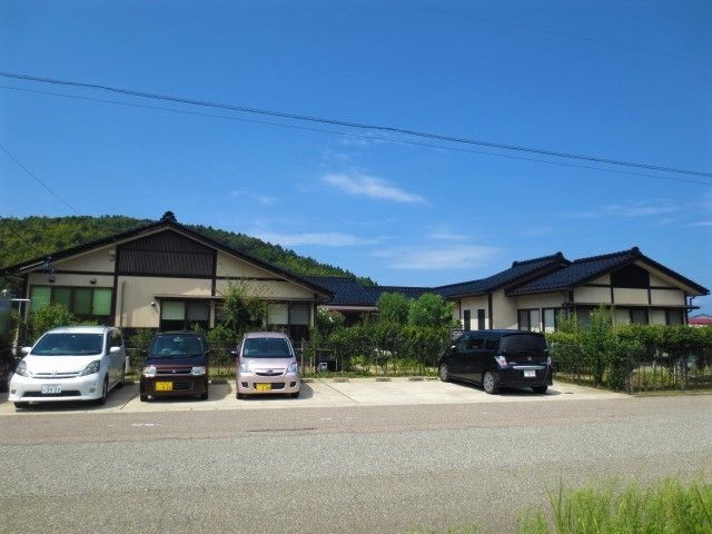 平屋建ての建物の前に車が4台停まっている。空は青空が広がっている